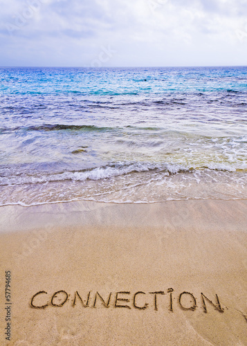 Connection word written on sand, with waves in background