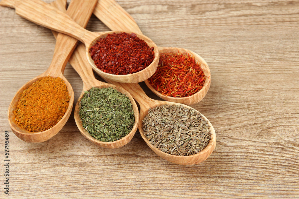 Assortment of spices in wooden spoons on wooden background Assortment of spices in wooden spoons on wooden background