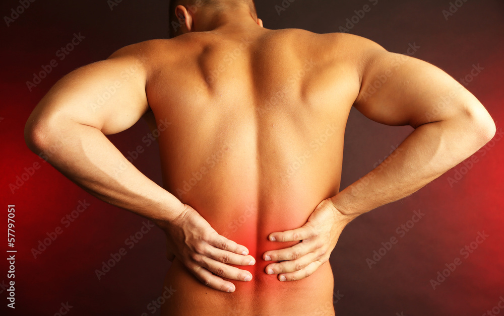 Young man with back pain on dark background