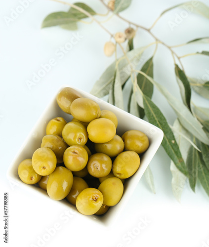 Olives in bowl with branch isolated on white