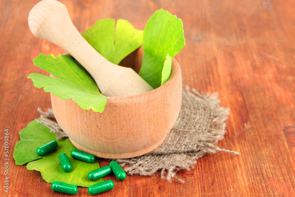Ginkgo biloba leaves in mortar and pills on wooden background Ginkgo biloba leaves in mortar and pills on wooden background