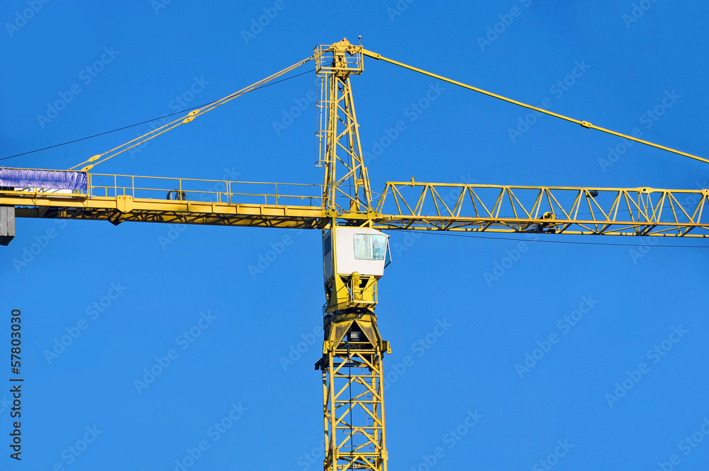 Yellow construction tower crane against blue sky