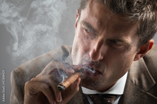 hard gaze businessman while smoking a cuban cigar