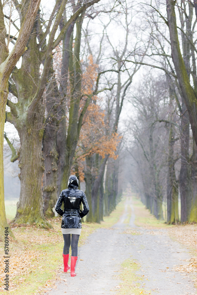 woman wearing rubber boots in autumnal alley woman wearing rubber boots in autumnal alley