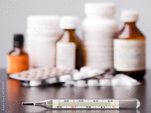Mercury thermometer and medical pills on background