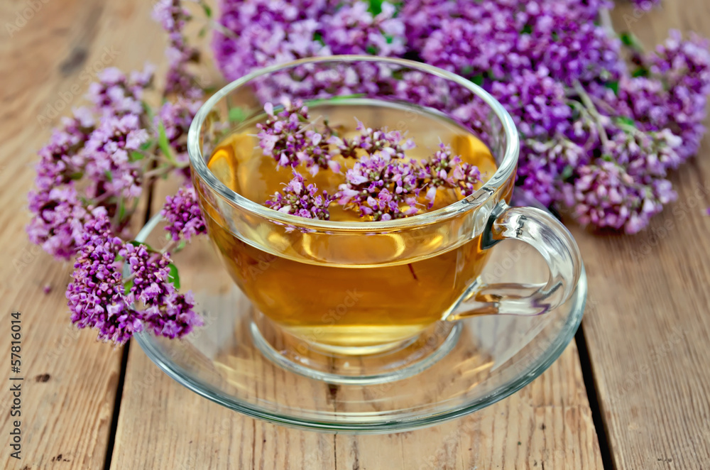 Fototapeta premium Herbal tea from oregano in a glass cup on a board