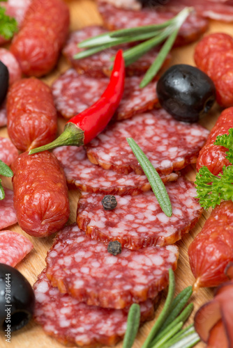 Assorted meats and sausages on a wooden board, close-up