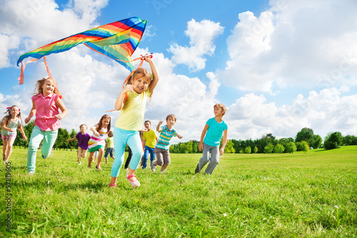 Cute group of kids run with kite