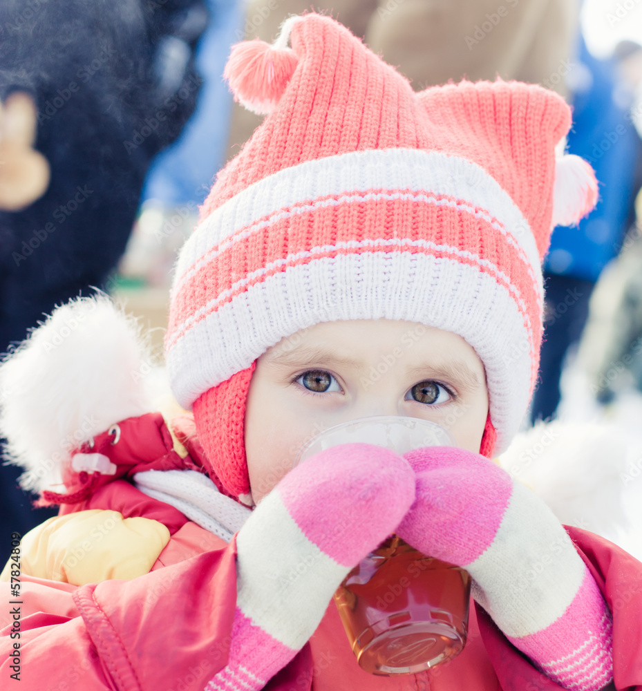 Little girl drinks tea from a plastic cup