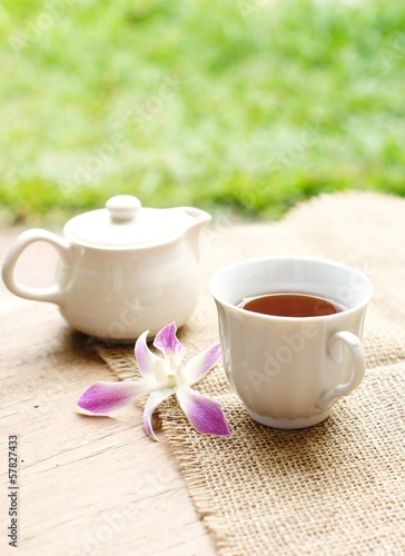 cup of tea with orchid flower on wooden table