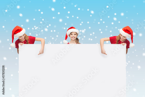 children in santa helper hats with blank board © Syda Productions