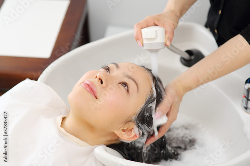 シャンプー台で髪を洗う女性