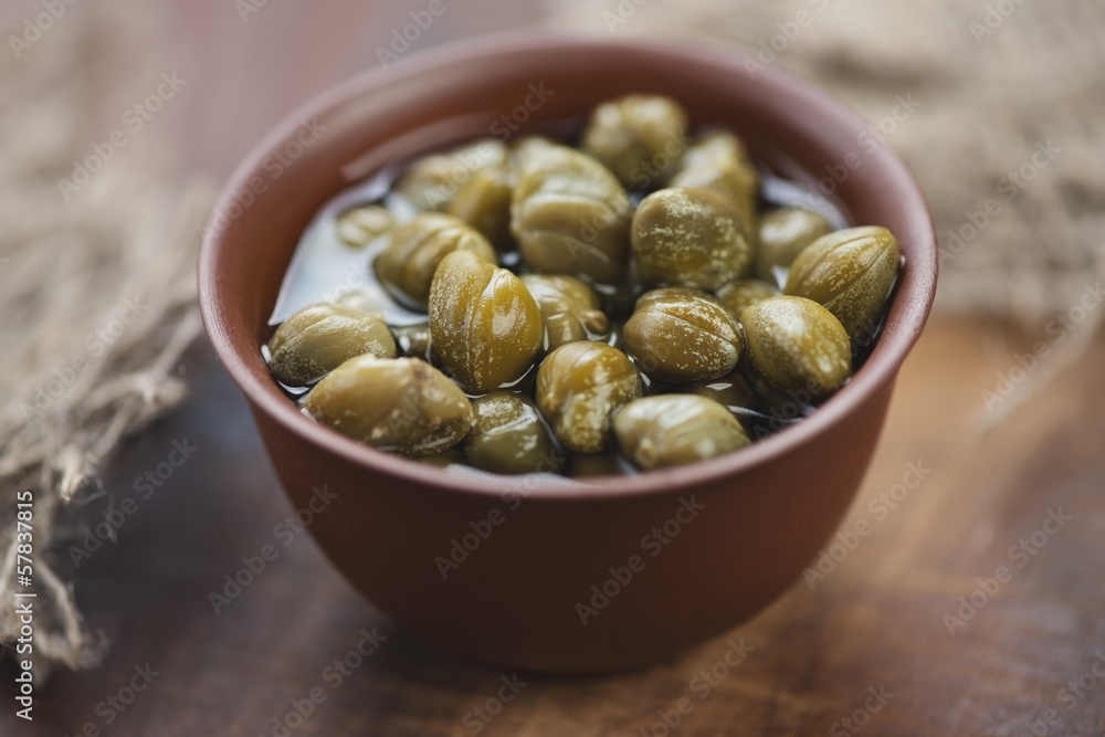 Pickled capers in a ceramic dish, studio shot Pickled capers in a ceramic dish, studio shot