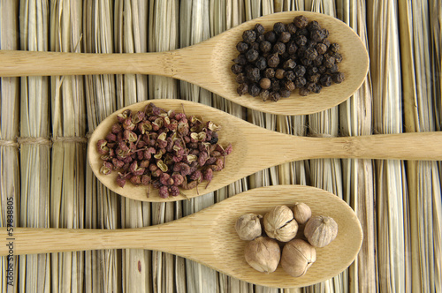 Allspice, peppercorns , nutmeg seeds on wooden spoon photo