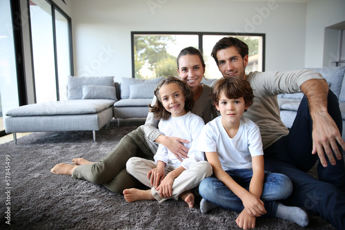 Happy family portrait at home sitting on carpet photo