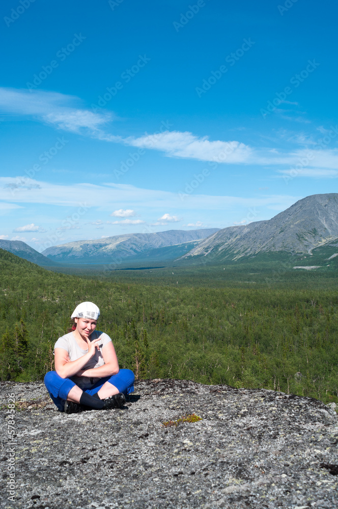 Woman sitting on mountain top and looking at camera