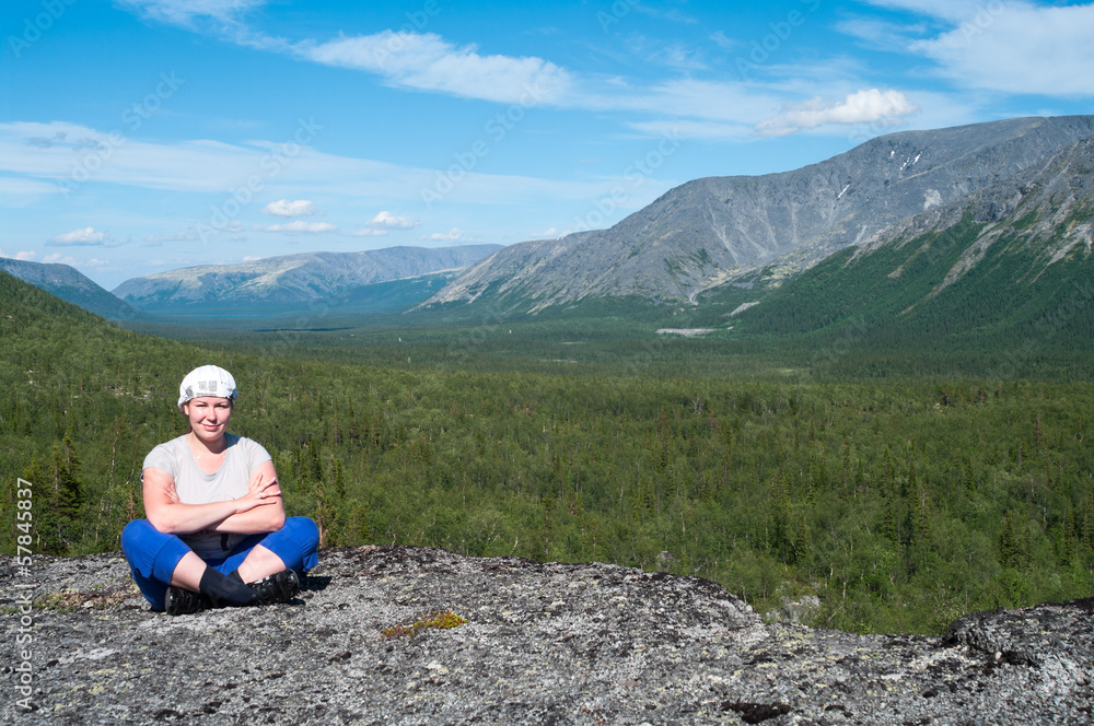 Woman sitting on mountain top and looking at camera. Copy space