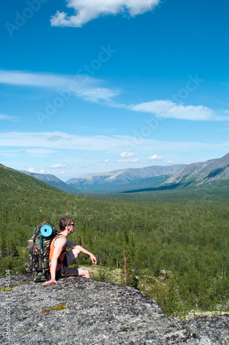 Male hiker sitting and relaxing at the summit with backpack
