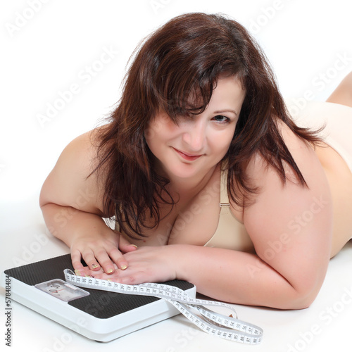 Overweight woman with a weighing machine and measure tape. photo