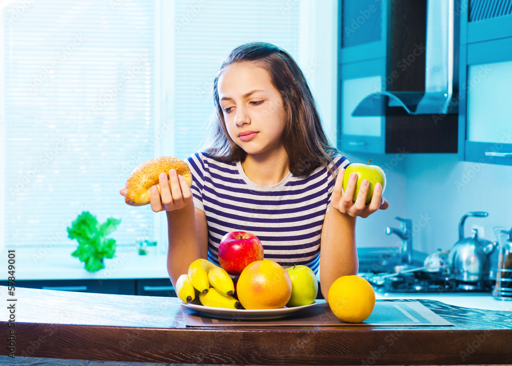 Obraz premium Beautiful Young Woman choosing between Fruits and Sweets