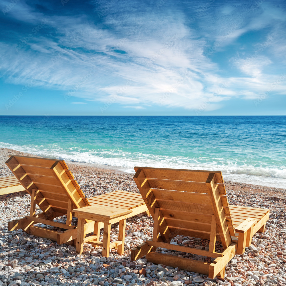 Two wooden sun loungers stand on the beach