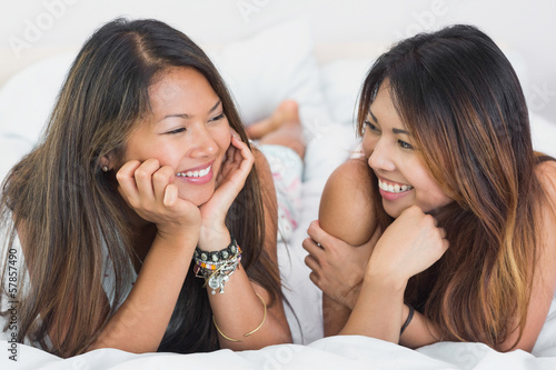 Two nice young girls lying on a bed photo