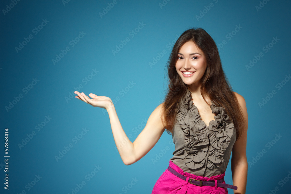 beautiful teen girl showing something with hand, over blue beautiful teen girl showing something with hand, over blue