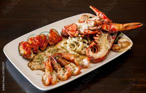 Grilled red lobster and seafood on platter.