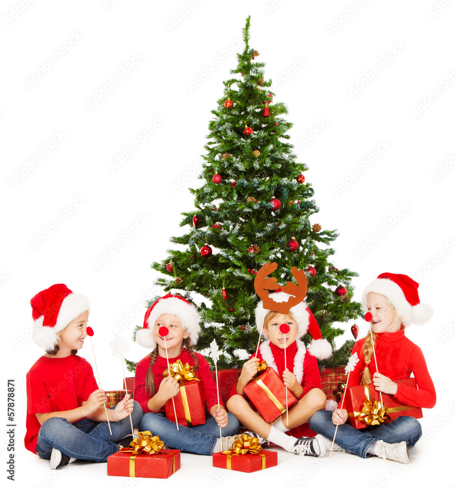 Christmas children in Santa hat playing presents under fir tree Christmas children in Santa hat playing presents under fir tree