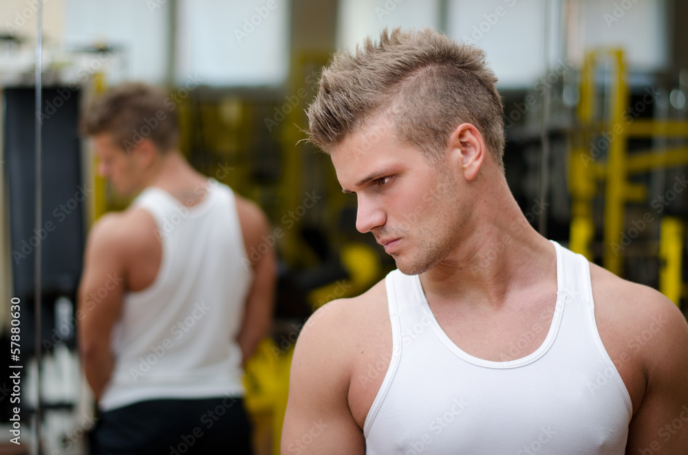 Young man in gym resting and looking down to a side