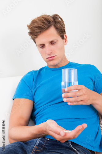 Man Holding Medicine And Glass Of Water