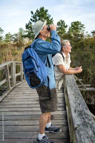 Senior Couple Hiking and Birdwatching on Old Wooden Foot Bridge photo