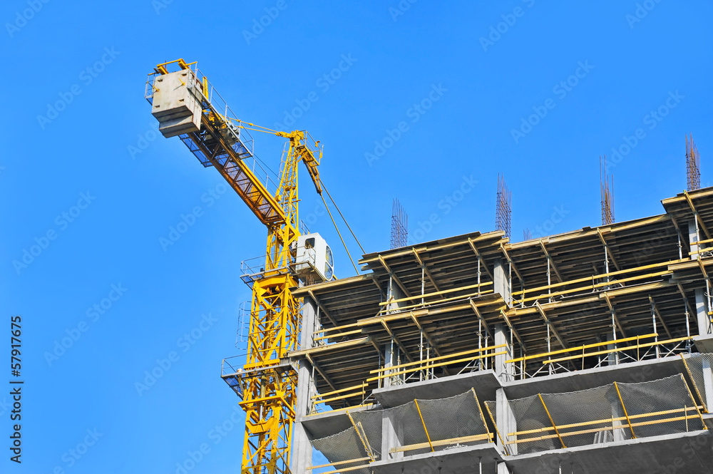 Fototapeta premium Crane and building construction site against blue sky