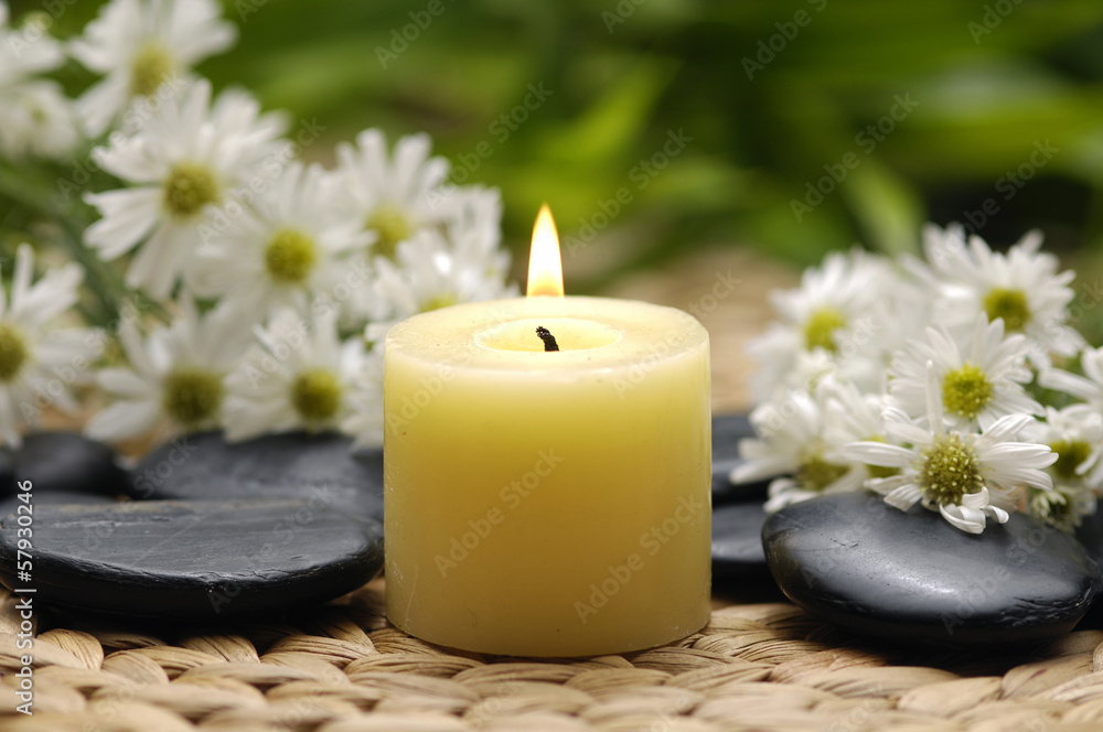 gerbera and burning candle with zen stones on wicker mat