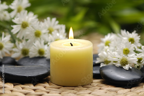gerbera and burning candle with zen stones on wicker mat
