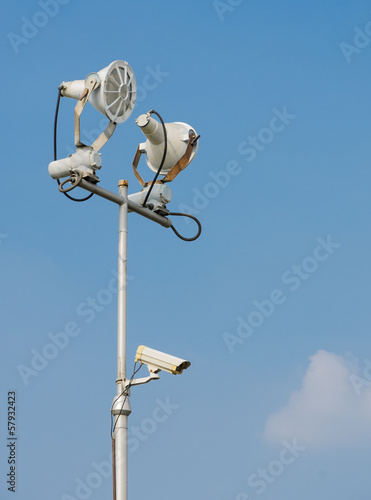 Floodlight with surveillance cameras in blue sky