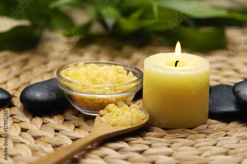 burning candle with bamboo leaves salt on wooden spoon on woven wicker mat