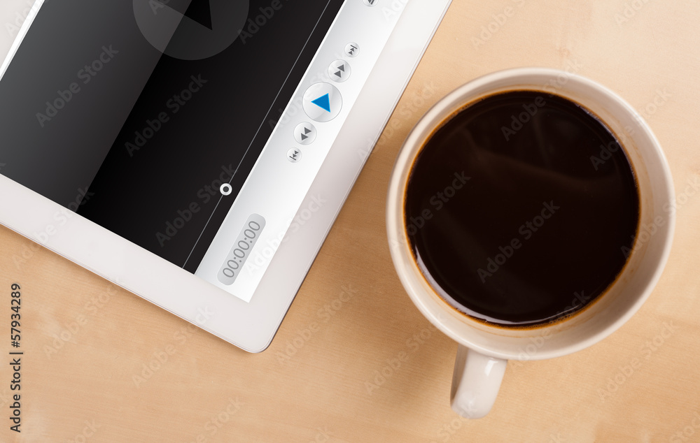 Tablet pc showing media player on screen with a cup of coffee on Tablet pc showing media player on screen with a cup of coffee on