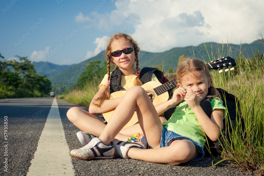 two girls with backpacks sitting on the road