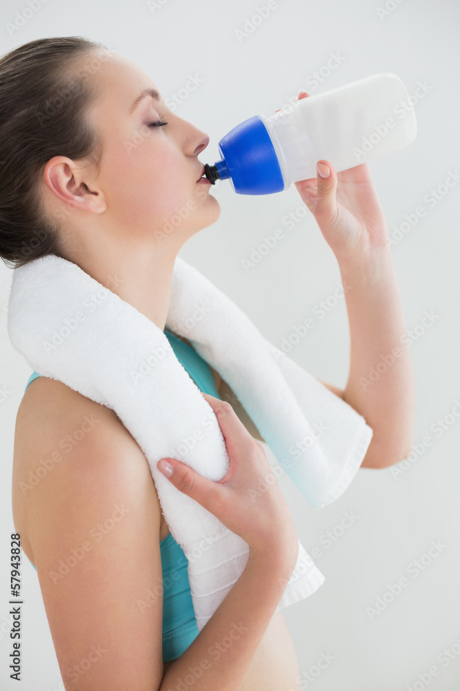 Woman with dumbbells drinking water against wall Woman with dumbbells drinking water against wall