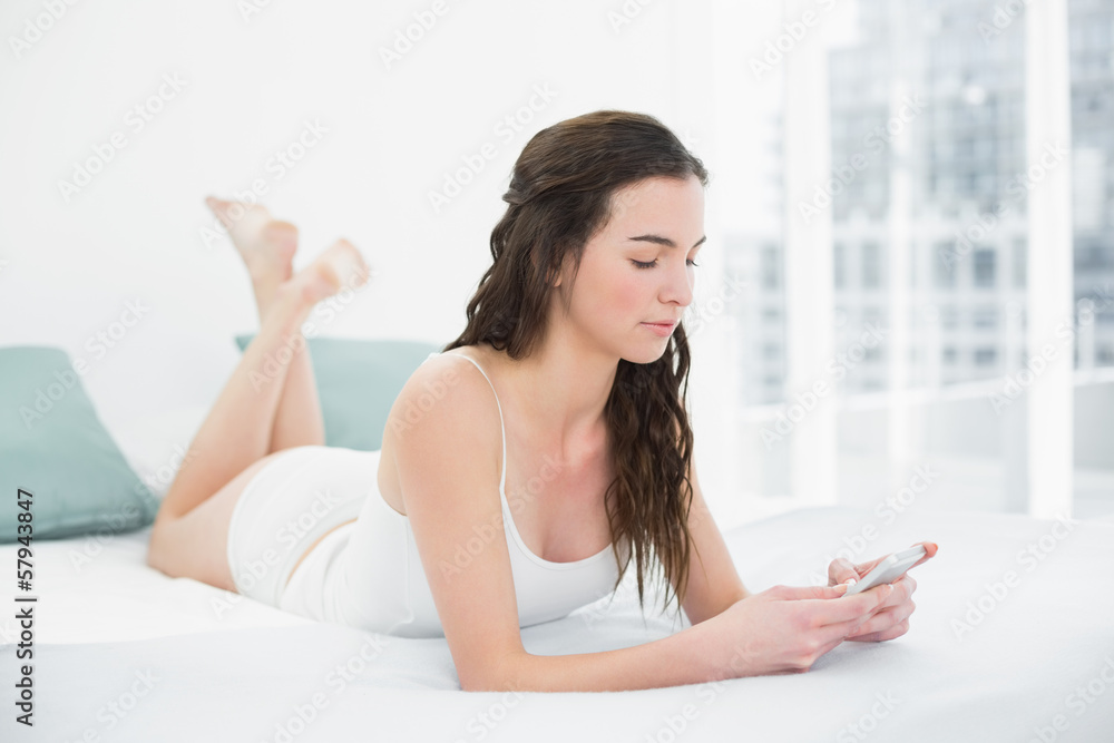 Serious woman looking at mobile phone in bed Serious woman looking at mobile phone in bed