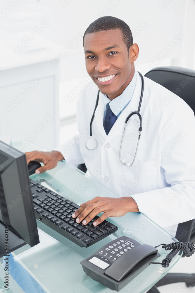 Smiling doctor using computer at medical office Smiling doctor using computer at medical office