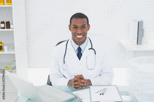 Smiling doctor with laptop at medical office