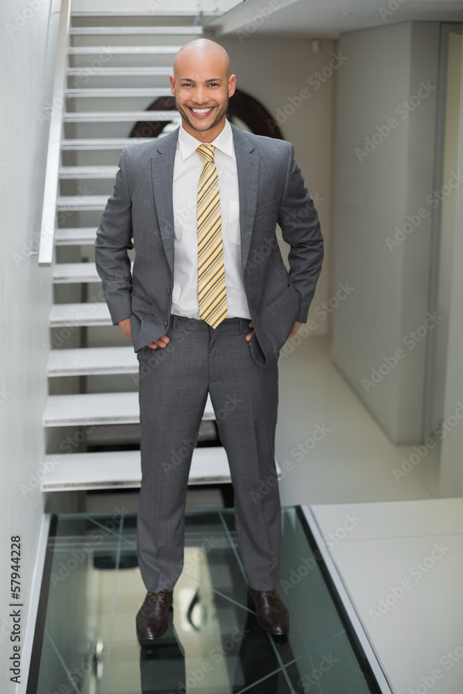 Elegant businessman standing against staircase in office