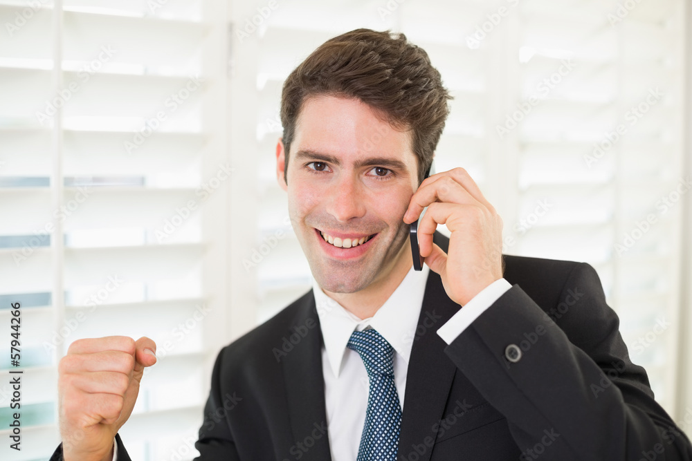 Portrait of smiling businessman using mobile phone while clenchi Portrait of smiling businessman using mobile phone while clenchi