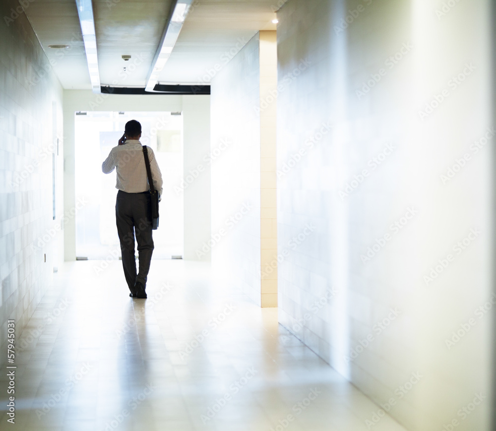 Businessman walking down the corridor on the phone Businessman walking down the corridor on the phone