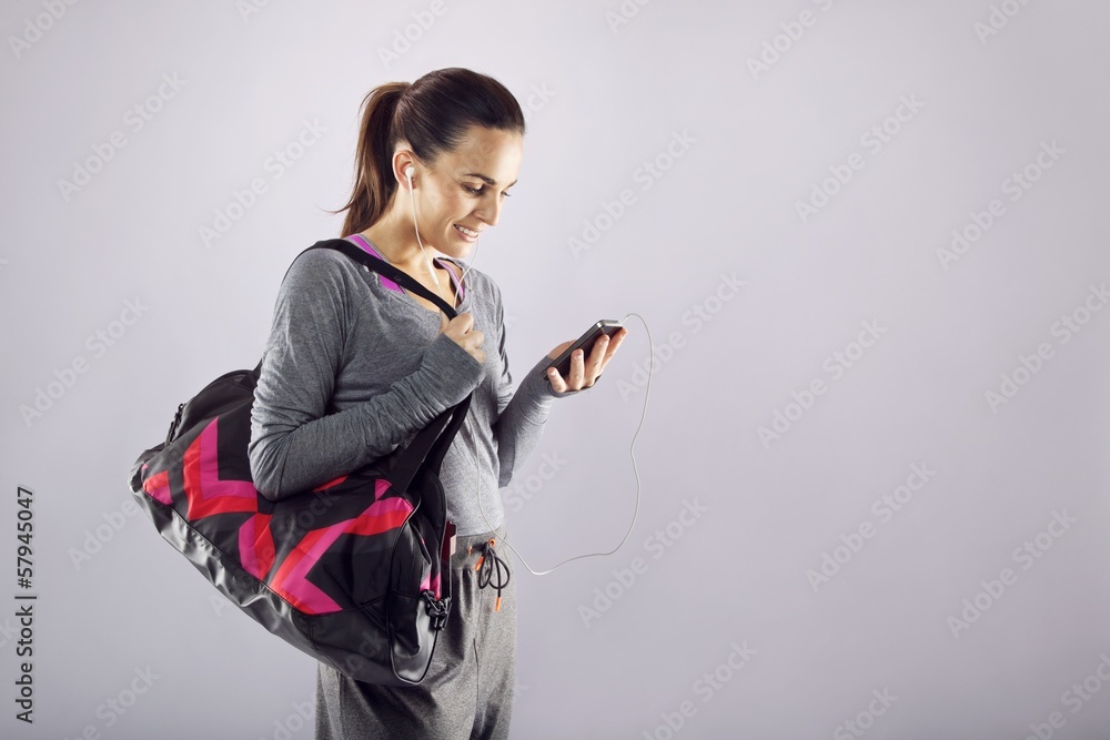 Naklejka premium Fitness woman with gym bag listening music