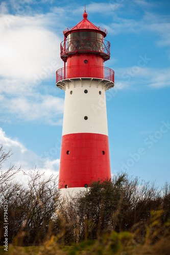 rot weisser leuchtturm vor blauem himmer wolken ostsee