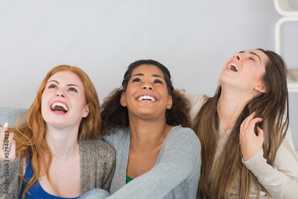 Fototapeta premium Cheerful young female friends laughing at home