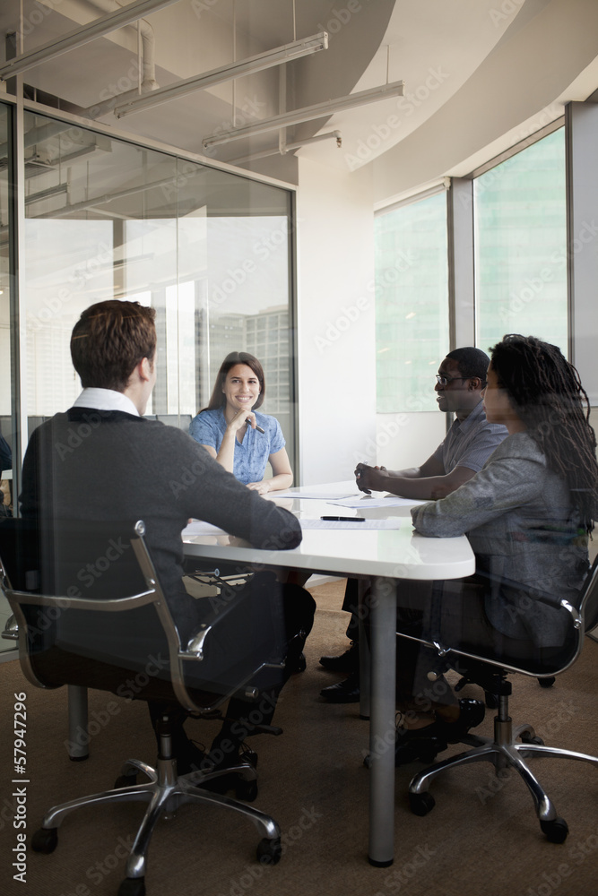 Four business people sitting at a conference table and discussing during a business meeting Four business people sitting at a conference table and discussing during a business meeting
